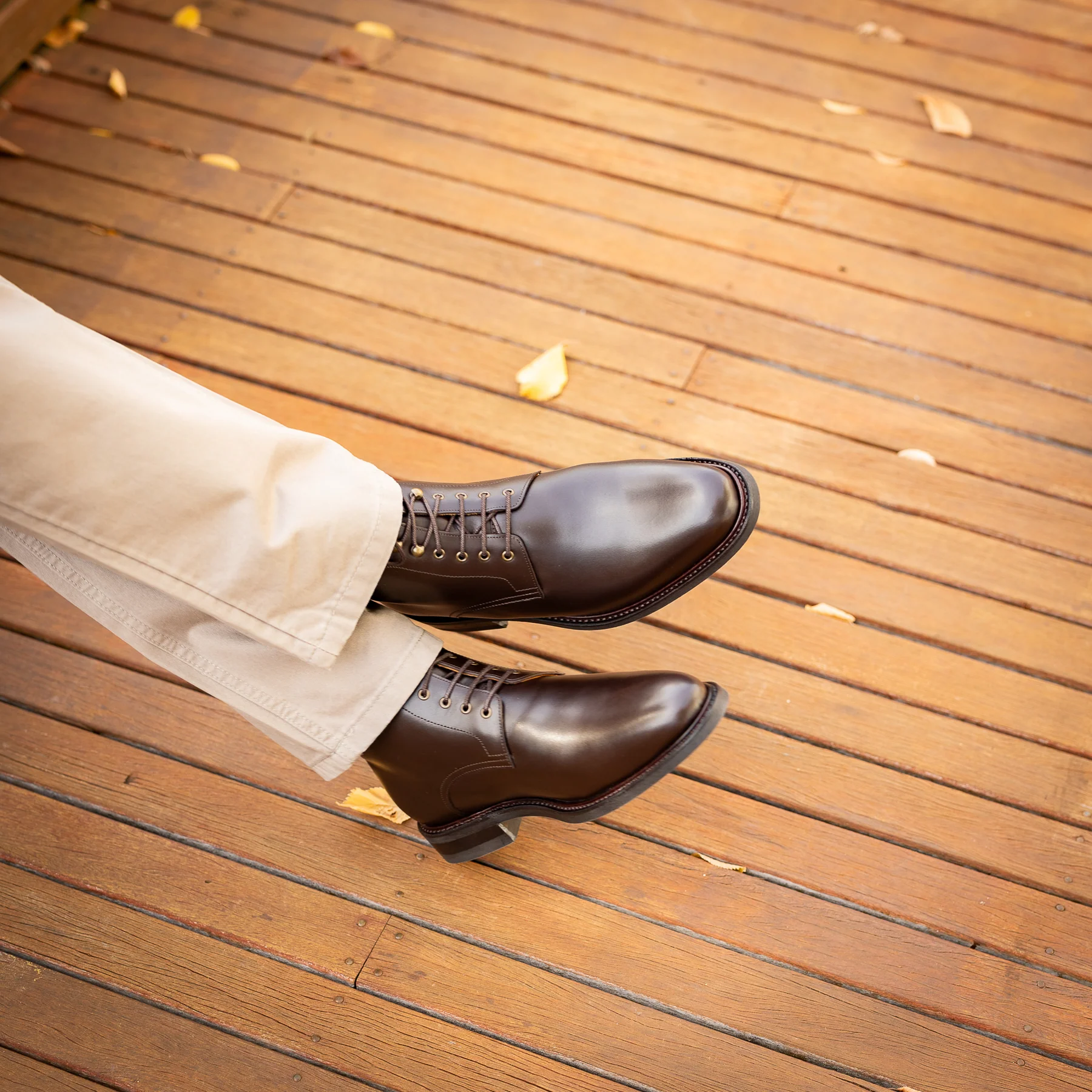 Brown leather shoes and white pants on a wooden floor