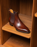 Brown leather Chelsea boot on a wooden shelf