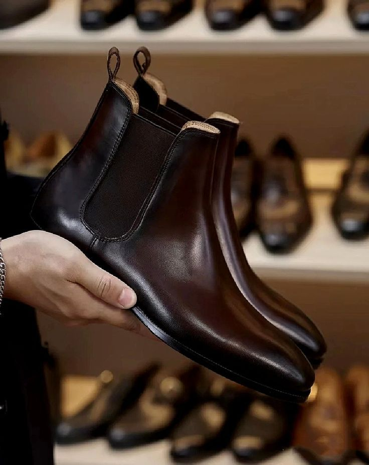 Person holding a brown leather boot with shoes displayed in the background